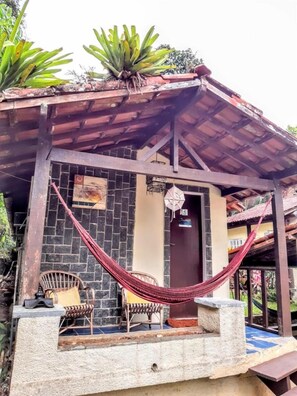 A rustic building with a tiled exterior, a hammock, and a door marked with the number 5. - Pousada L'Auberge (Angra dos Reis)