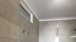 A modern bathroom with a glass shower enclosure, a white toilet, and a small window. - New and complete house, 300 mtrs from Manta Rota beach (Vila Nova de Cacela)