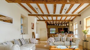 A spacious living room with a wooden coffee table, a sofa, and a dining area with a table set for two. - 3 bedroom accommodation in Tacolneston, near Wymondham (Tacolneston, near Wymondham)