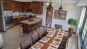 A modern kitchen with wooden cabinets, a central island, and pendant lighting. - El Cubil 8 (Sardinal)