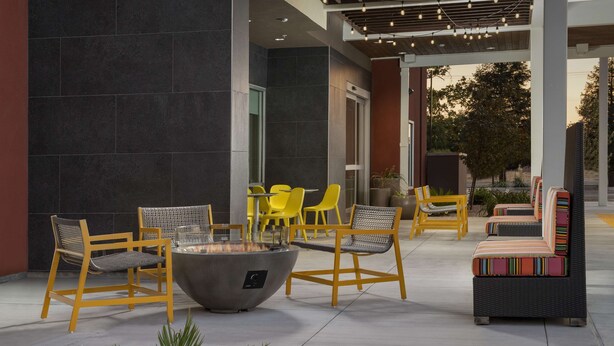 Un espace extérieur aménagé avec des chaises jaunes et un foyer.