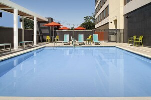 Una piscina al aire libre, sombrillas, sillones reclinables de piscina