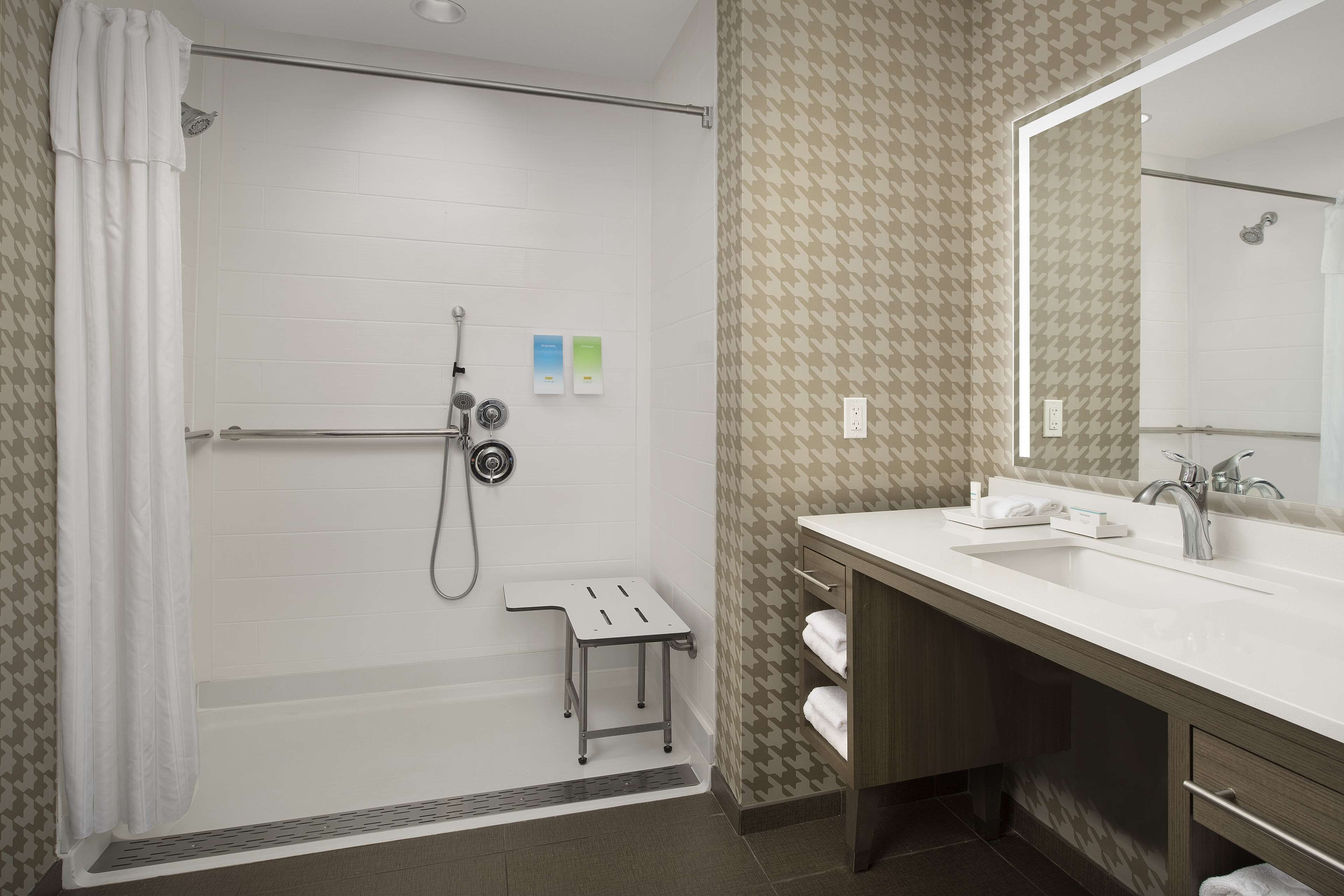 A modern bathroom with a shower, a vanity with a mirror, and a small step stool.