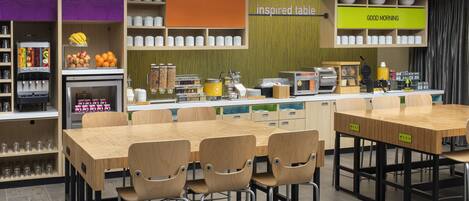 A modern kitchen with a central island, bar stools, and a variety of kitchen appliances and storage.
