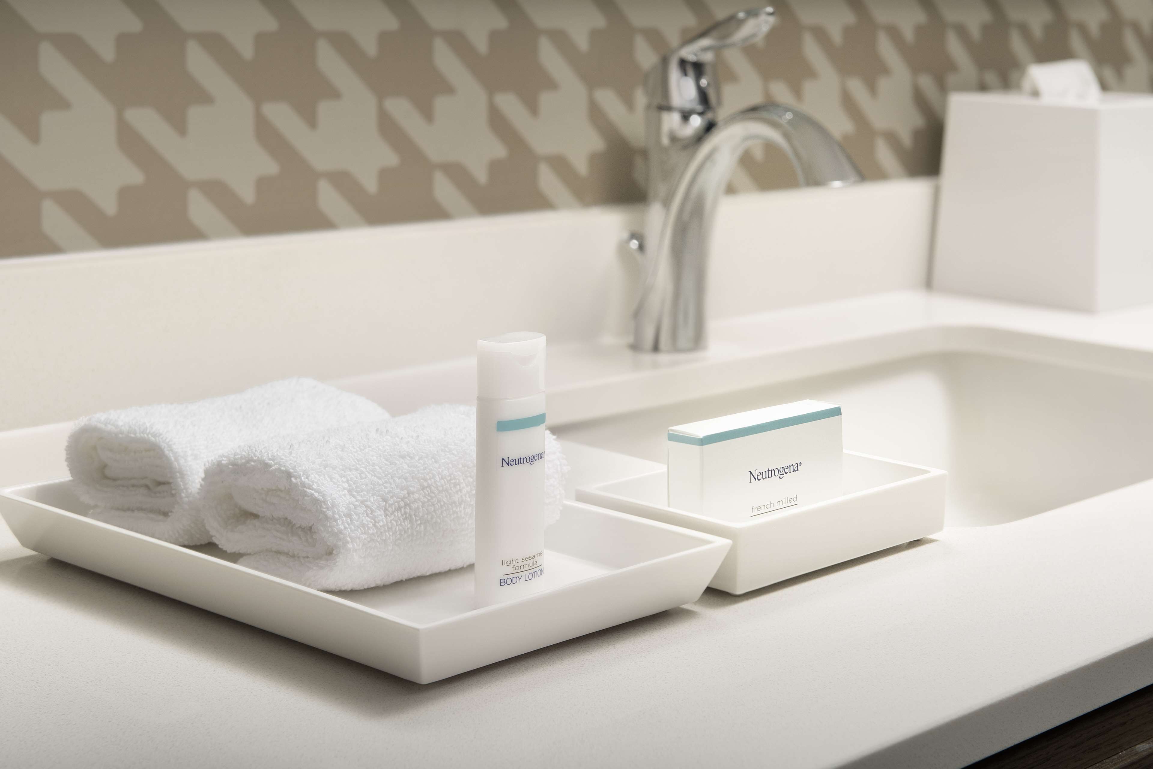 Un lavamanos con una toalla blanca y una botella de crema corporal Neutrogena.
