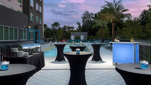 Un bar panoramico con tavoli rotondi, una piscina e posti a sedere all'aperto.