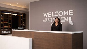 Ein Empfangsschalter mit einem Schild, auf dem 'Welcome to the Golden State' und ein Schild mit 'Hilton Honors' stehen.