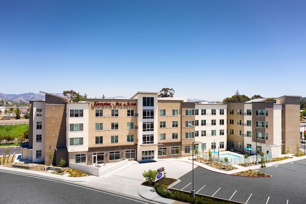 A multi-story hotel with a modern design, featuring a prominent sign, a swimming pool, and a parking lot. - Hampton Inn & Suites El Cajon San Diego (El Cajon)