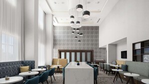 Eine moderne Hotelhalle mit einer zentralen Bar, Sitzbereichen und einem gemusterten Teppich.