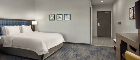A hotel room with a bed, a desk, and a door leading to another room.