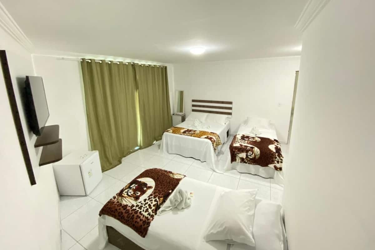 Ein Hotelzimmer mit zwei Betten, einem Flachbildfernseher, einem Schreibtisch und einem Fenster mit Vorhängen.