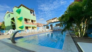 Una piscina con fuente acuática, rodeada de una terraza con baldosas y sillones de descanso.