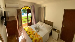 Un dormitorio con cama, mesita de noche, televisor y aire acondicionado.