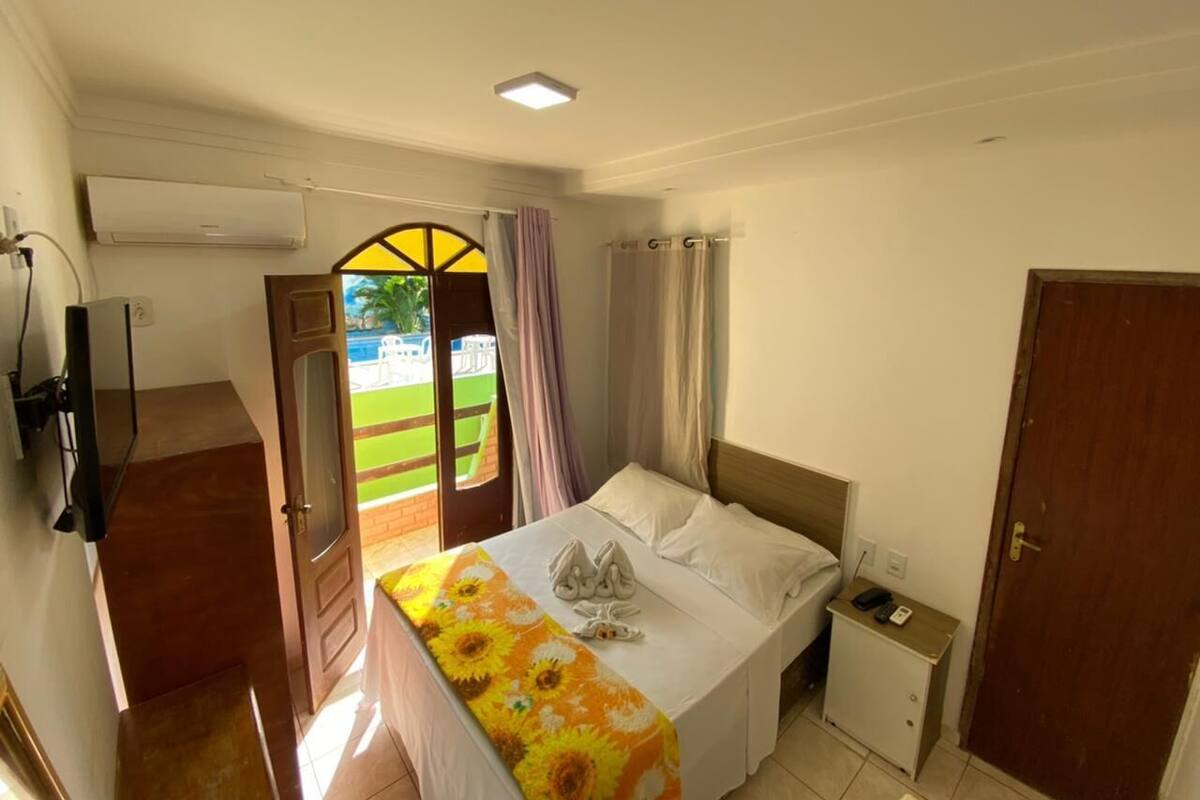Ein Schlafzimmer mit Bett, Nachttisch, Fernseher und Klimaanlage.