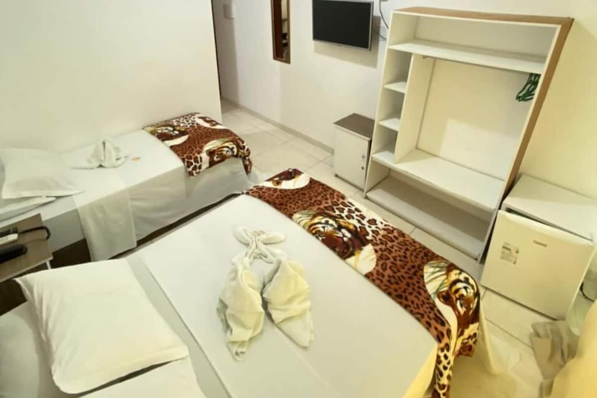Ein Hotelzimmer mit zwei Betten, einem Fernseher, einem Schrank und einem Schreibtisch.