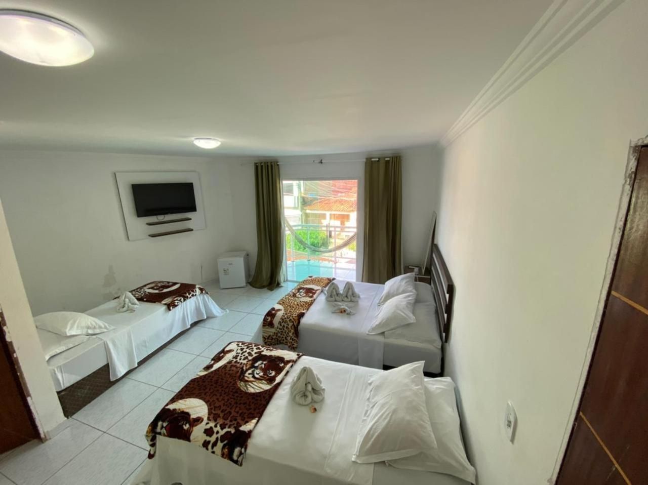 Une chambre d’hôtel avec deux lits simples, une télévision et une fenêtre avec des rideaux.