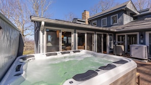 A hot tub with a wooden deck, a covered patio area, and an air conditioning unit. - Hearthstone- AppSki Mtn home with it all: hot tub, game room, fire pit, pets! (Blowing Rock)