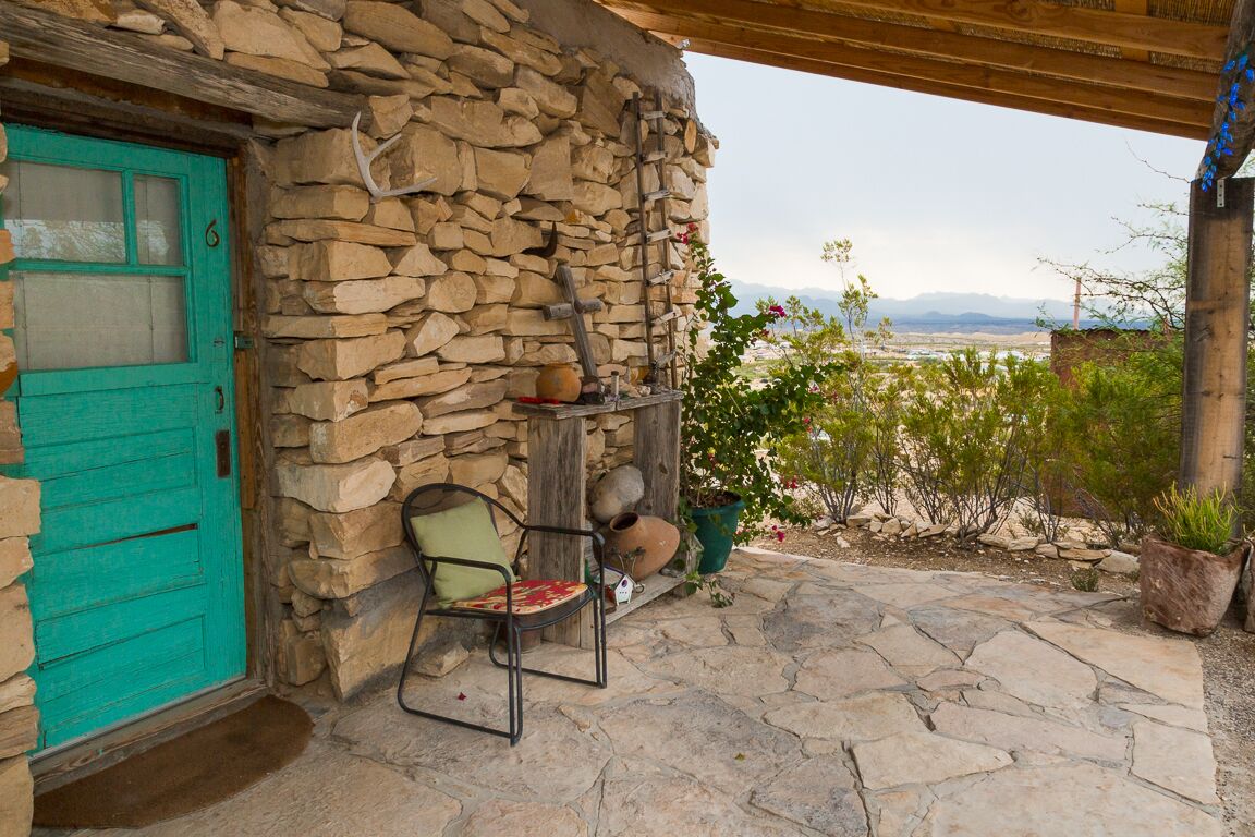 Um edifício de pedra com uma porta azul-turquesa, um banco de pedra e vista para a paisagem.