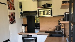 A compact kitchen with a built-in oven, microwave, and a small sink. - The green fee, close to the Golf course and 5 minutes from the lake (Giez)