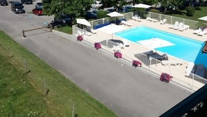 A swimming pool with lounge chairs and umbrellas, surrounded by greenery and mountains in the background. - The green fee, close to the Golf course and 5 minutes from the lake (Giez)