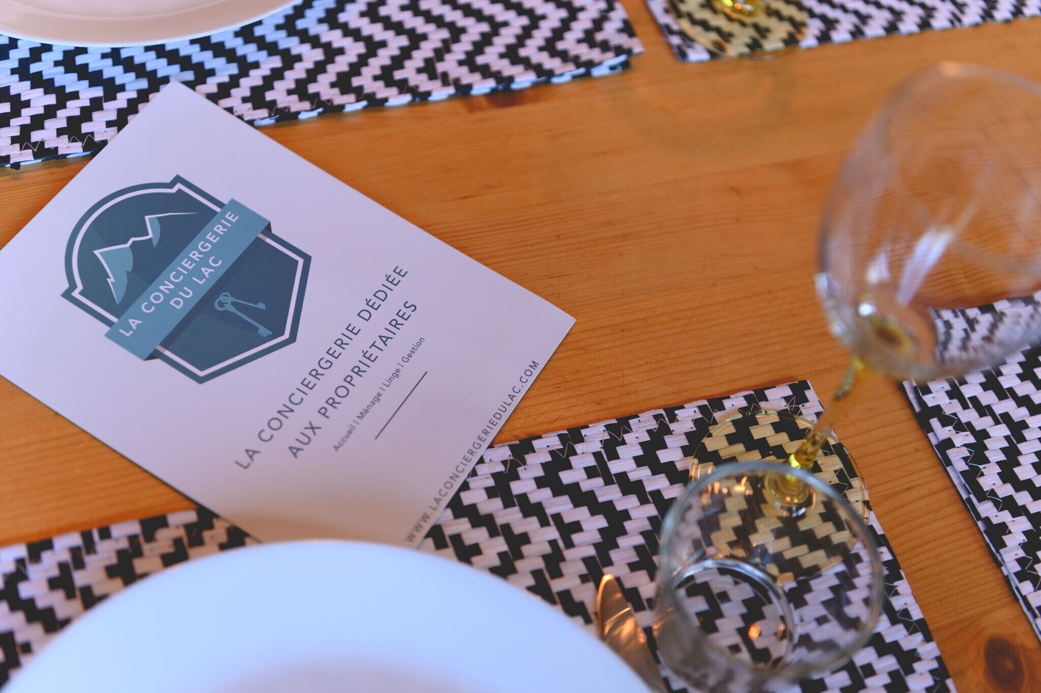 Een tafel met een placemat, een wijnglas en een visitekaartje.
