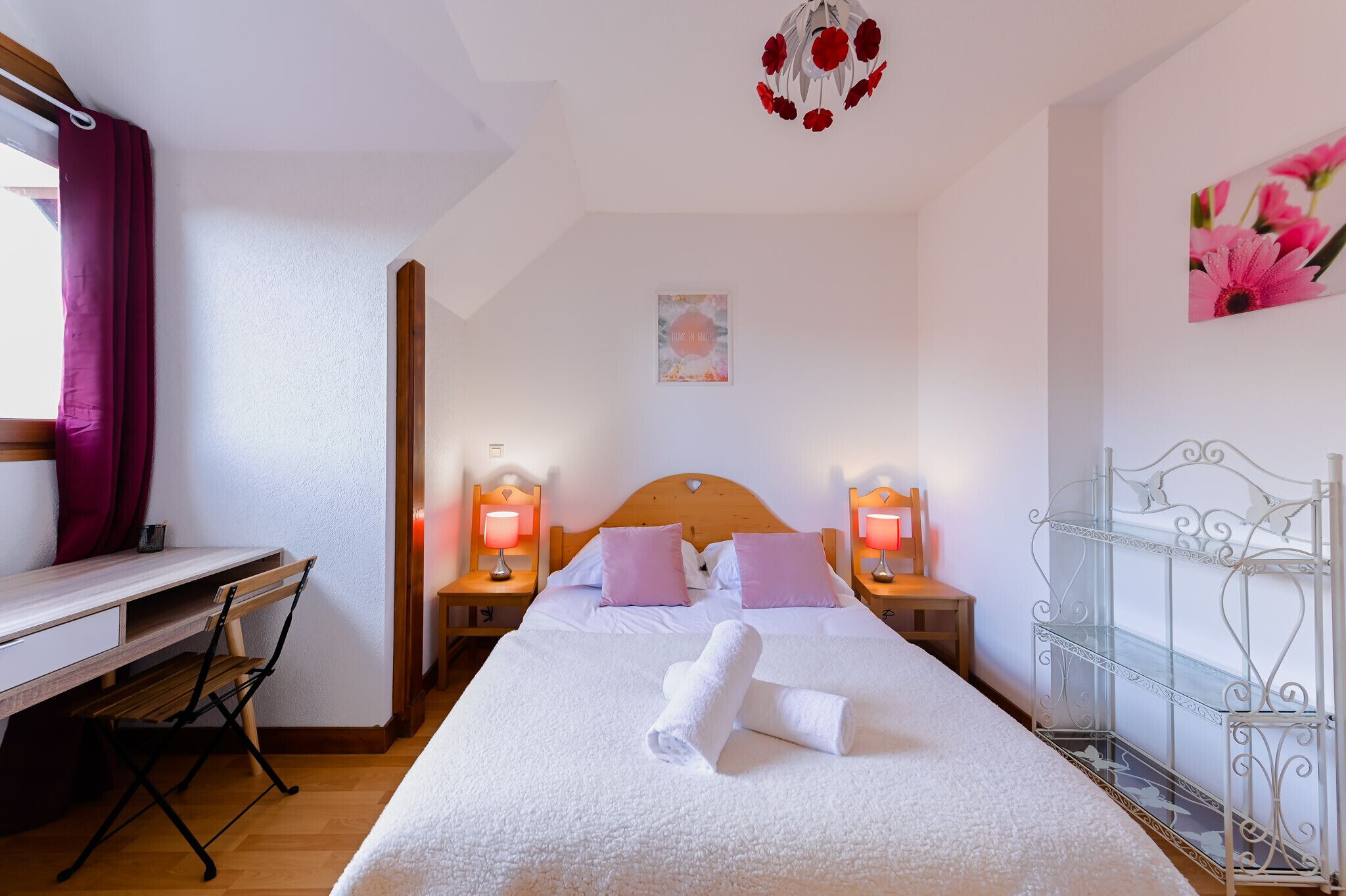 Una camera da letto ordinata con un letto, lampade ai comodini, una scrivania e una sedia.