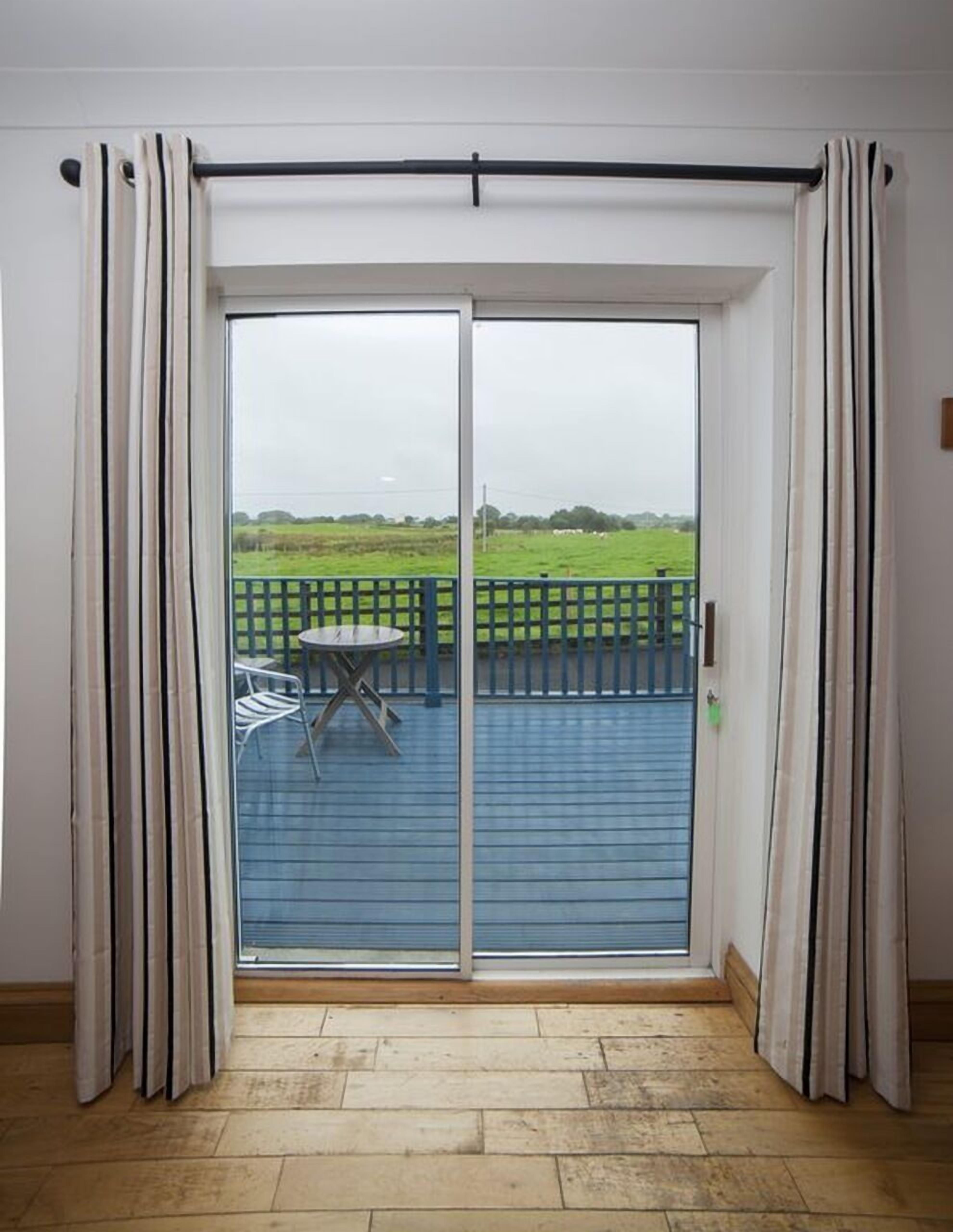 Een kamer met een schuifglazen deur naar een balkon met een tafel en stoelen.