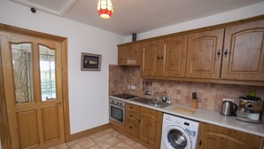 Une cuisine avec des meubles en bois, un lave-linge et un sol carrelé.
