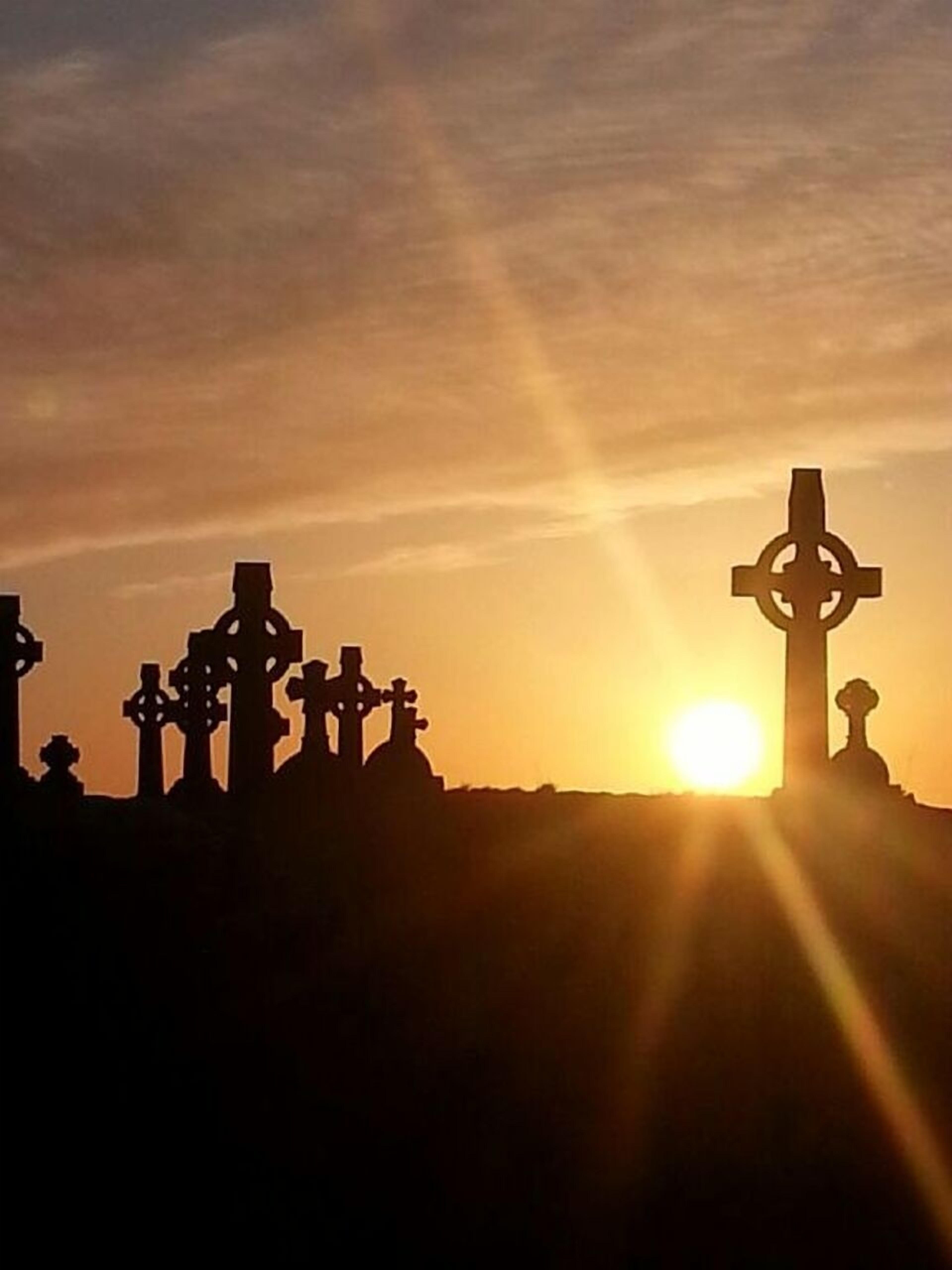 La silhouette de plusieurs croix se découpant sur un coucher de soleil.