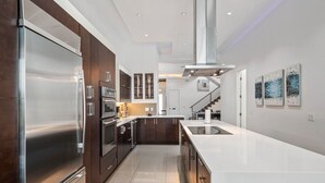 A modern kitchen with stainless steel appliances, dark wood cabinets, and a white countertop. - Liberty Holiday: Private Pool, Water Park, Golf View, Near Disney (Kissimmee)