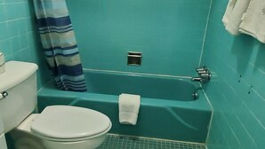 A bathroom with a white toilet, a bathtub, and a shower curtain. - Blue Haven Motel I-75 North Exit 128&129 (Rocky Top)