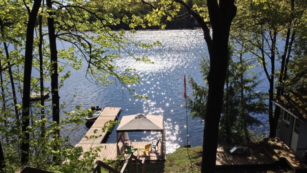 A wooden staircase leading to a dock with a covered seating area overlooking a lake. - Water access Island Cottage in sheltered cove (South Frontenac Region)