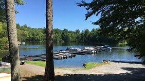 A lakeside dock with boats, a truck, and a person sitting by the water. - Water access Island Cottage in sheltered cove (South Frontenac Region)