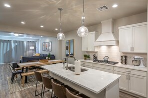 Een moderne keuken met witte kasten, een centraal eiland en hanglampen.