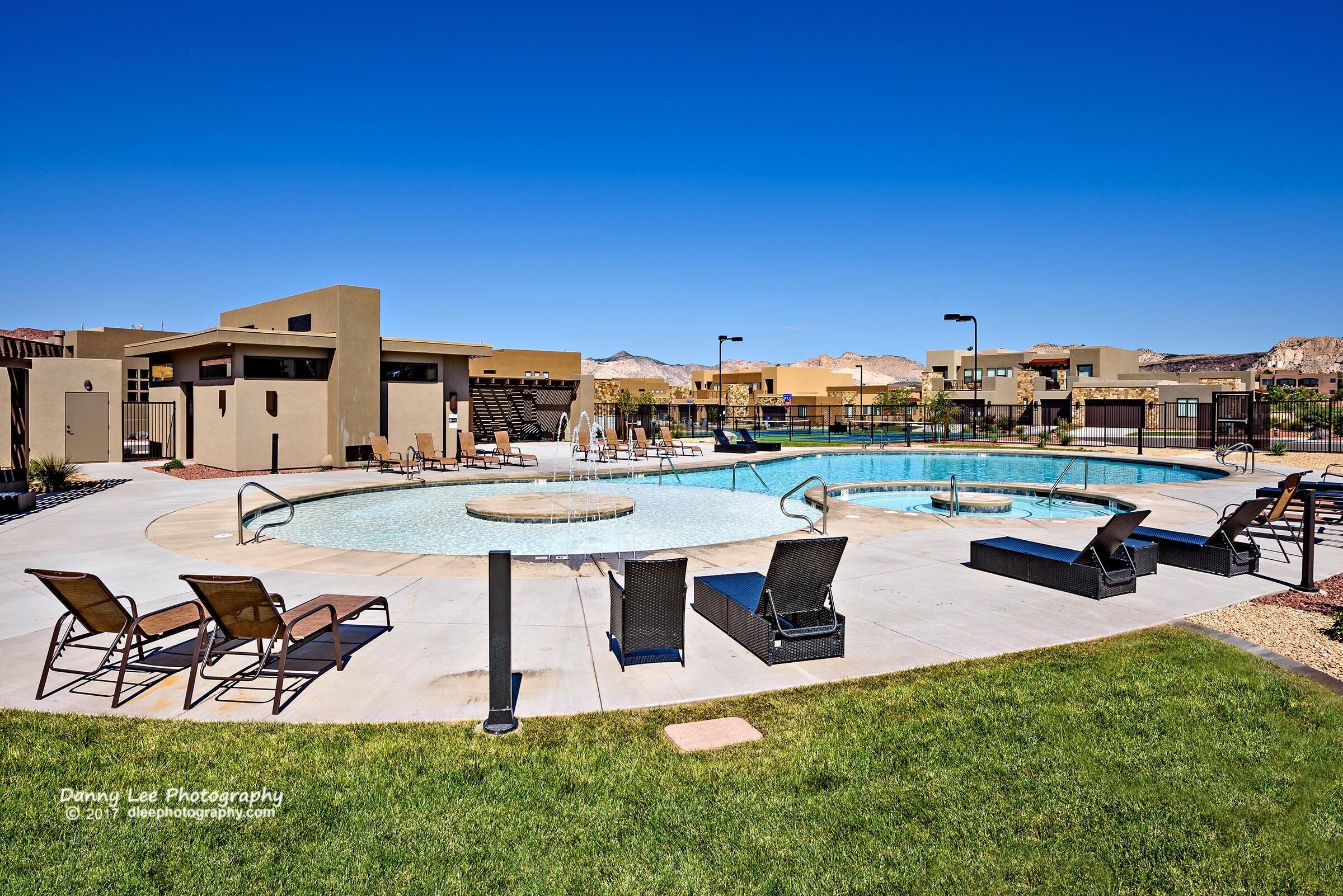 A pool area with lounge chairs, a swimming pool, and modern buildings in the background.