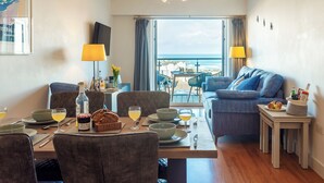 Ein Hotelzimmer mit Essbereich, einer Couch, einem Fernseher und Meerblick.