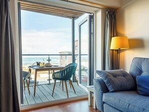 A room with a balcony, a table with chairs, a sofa, and a lamp. - 2 bedroom accommodation in Newquay (Newquay)