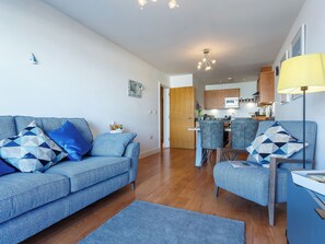 A modern living room with a sofa, a coffee table, and a dining area with chairs.
