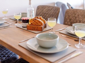 Una mesa de comedor con pan, vasos y una botella.