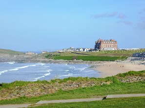 A coastal view with a large building, a beach, and a rocky shoreline.