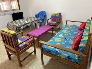 A room with a bed, two wooden chairs, a small table, and a blue chair.