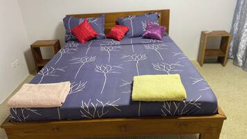 A bed with a blue floral bedspread, two wooden nightstands, and a wooden headboard.