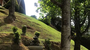 Un jardin aménagé avec une fontaine à plusieurs niveaux, des marches en pierre et une variété d’arbustes.
