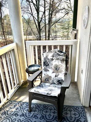 A covered porch with a single chair and a small table, a patterned rug, and a view of trees and hills. - INDOOR POOL! CLOSE TO DOLLYWOOD!! (Pigeon Forge)