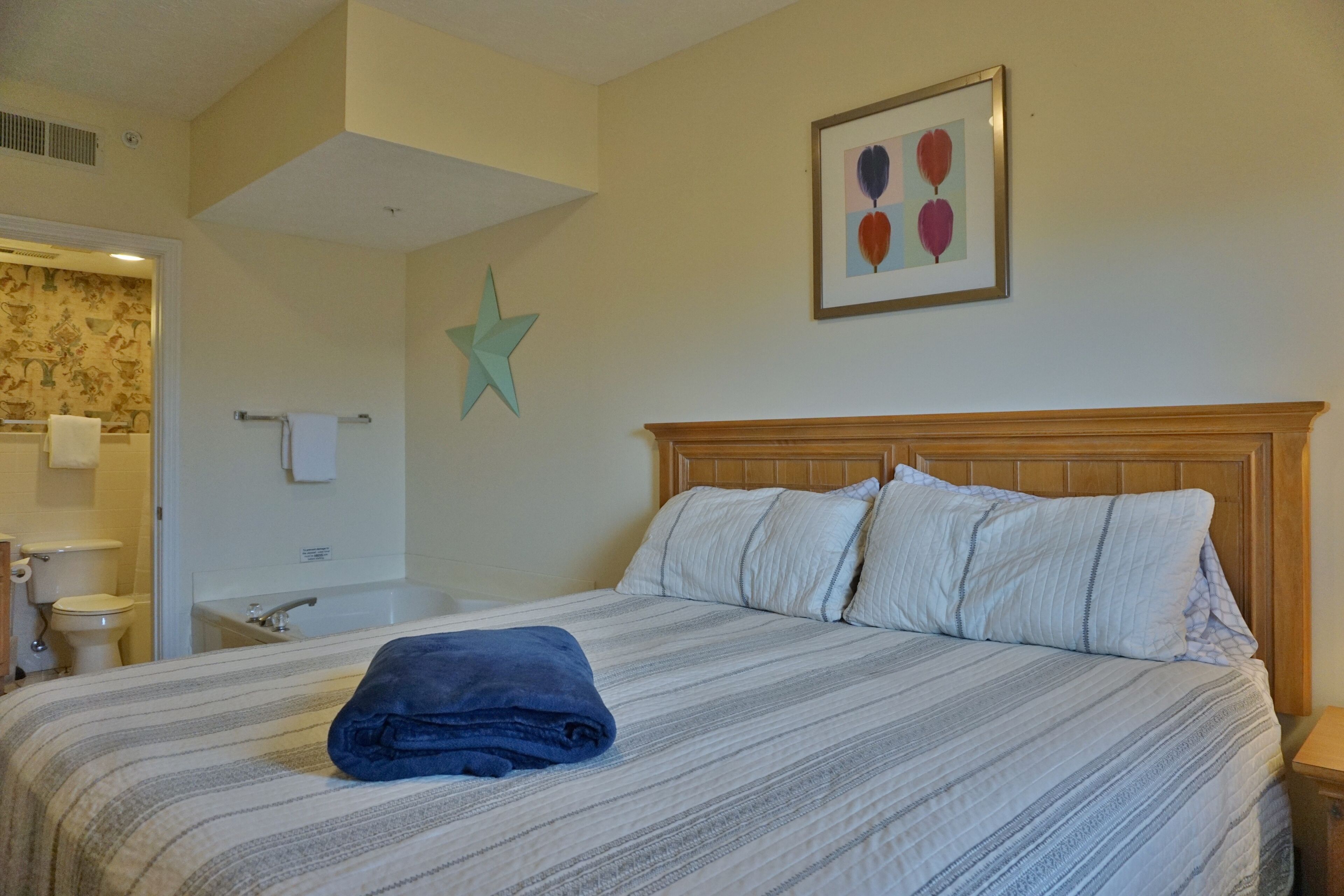 A hotel room with a bed, a star decoration on the wall, and a framed picture above the bed.