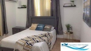 Une chambre à coucher comprenant un lit, une table de chevet, un appareil de climatisation, une petite étagère avec une plante et une œuvre d’art accrochée au mur.
