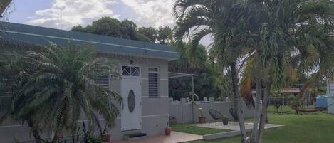 Una propiedad residencial con una pequeña casa, palmeras y un césped bien cuidado.