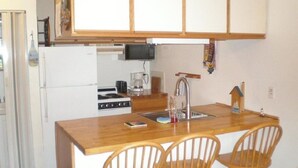 A compact kitchen with a wooden island, two bar stools, a sink, and a stove. - Great place for fisherman and bird watchers (Oak Harbor)