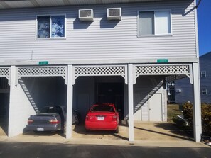 Um edifício com três garagens, dois aparelhos de ar condicionado e uma placa de rua indicando o endereço.