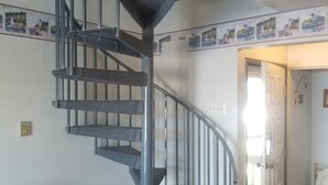 A compact living space with a spiral staircase, a patterned sofa, and a door leading to another room. - Great place for fisherman and bird watchers (Oak Harbor)